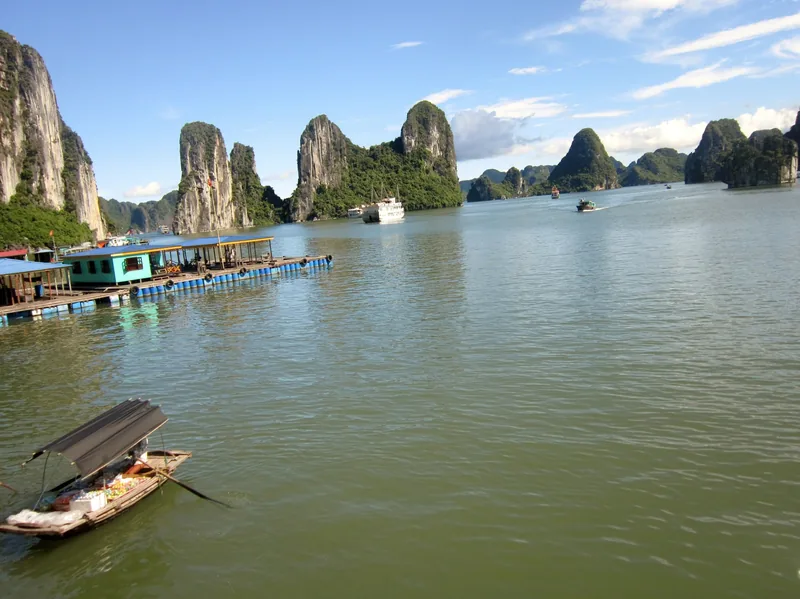 Những đảo đá vôi nhô lên trên mặt nước yên bình với thuyền và làng chài nổi ở Vịnh Hạ Long.