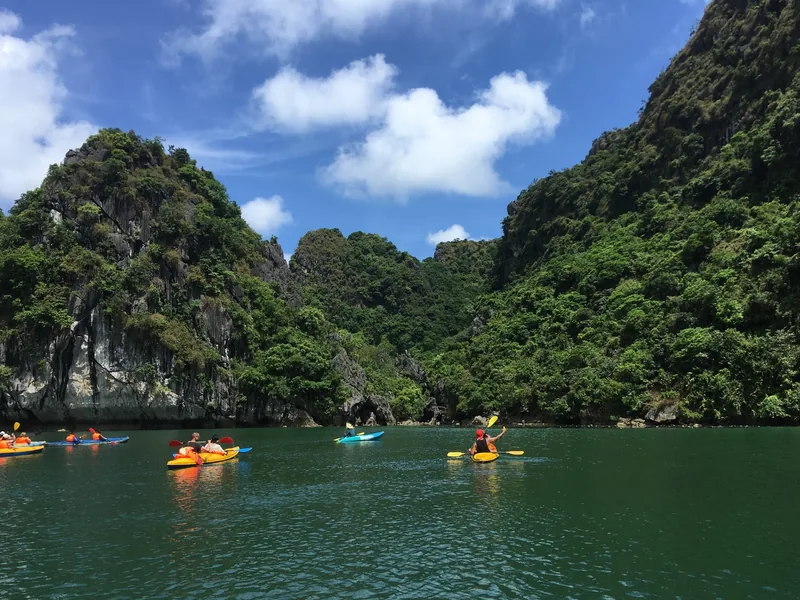 Du khách chèo thuyền kayak giữa những đảo đá vôi sừng sững trên làn nước xanh ngọc của vịnh Hạ Long.