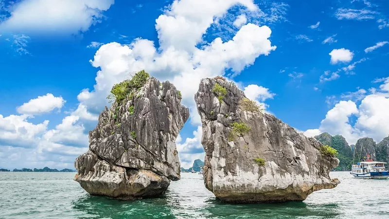 Hai đảo đá vôi nổi tiếng Hòn Trống Mái nhô lên giữa làn nước xanh dưới bầu trời nắng ở vịnh Hạ Long.