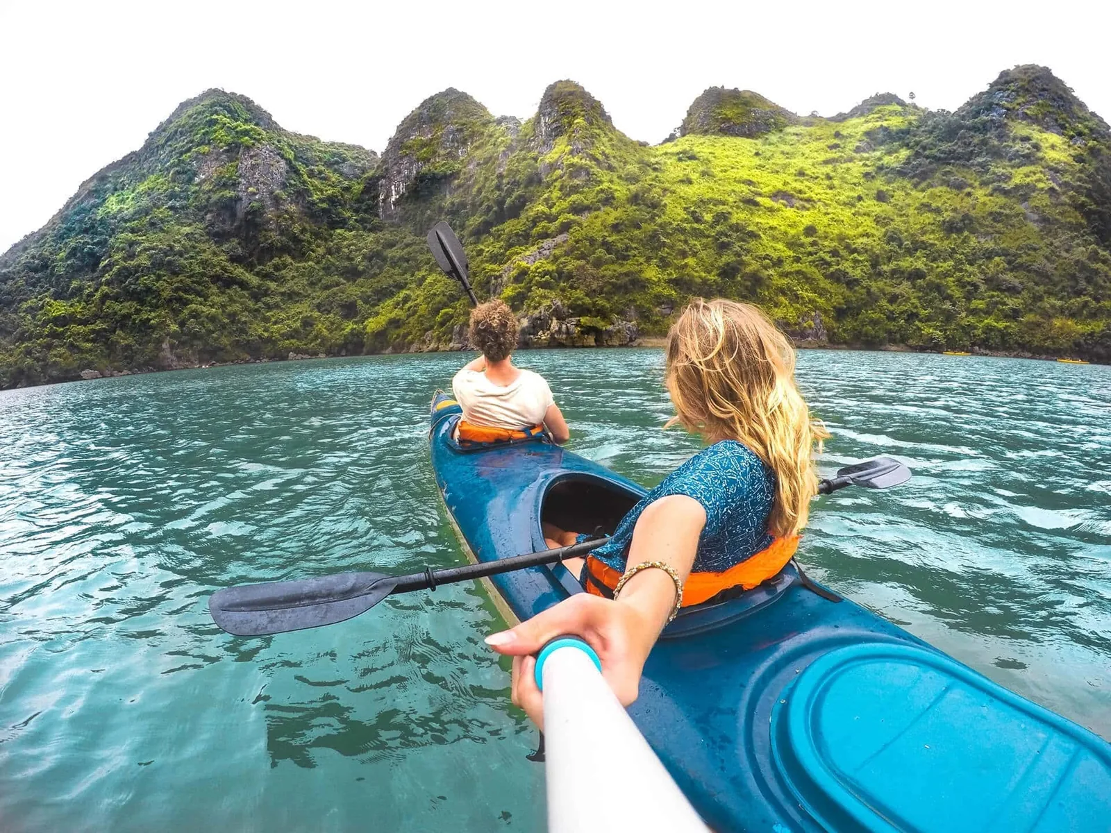 Một cặp đôi chèo kayak trên làn nước xanh ngọc giữa những núi đá vôi ở vịnh Hạ Long.