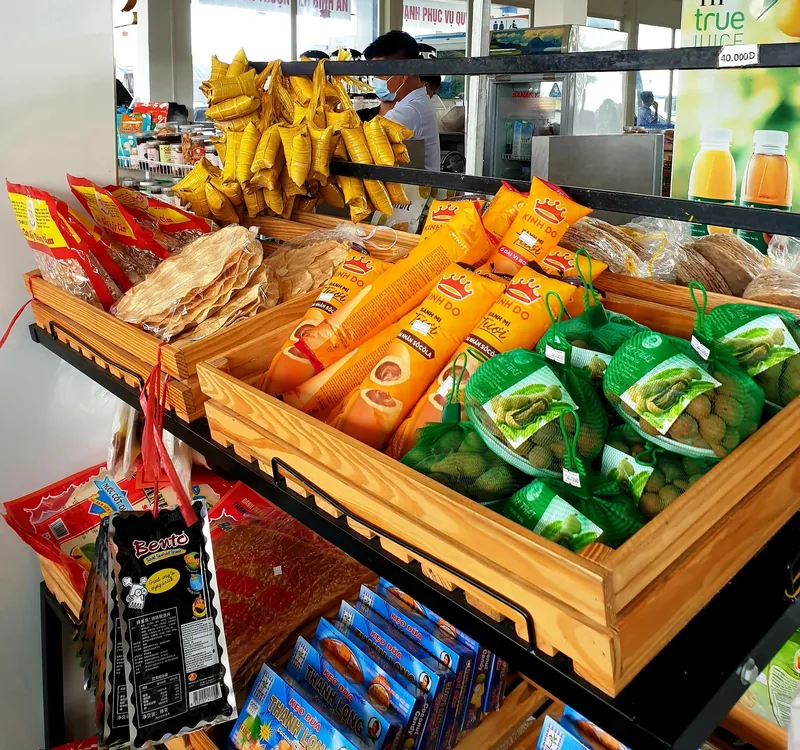 Kệ hàng tại trạm dừng chân ở Tiền Giang bày bán các loại đặc sản đóng gói, chuối khô và trái cây.