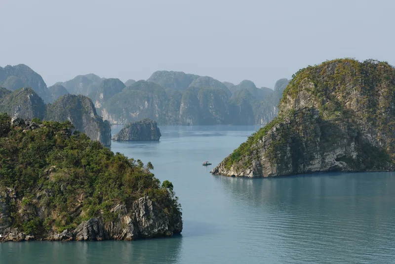 Những đảo đá vôi nhô lên từ làn nước xanh ngọc tĩnh lặng ở vịnh Hạ Long, Việt Nam.